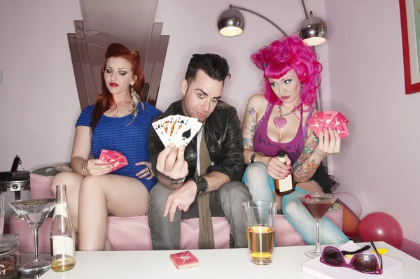 Портрет мужчины, держащего игральные карты с женщинами, сидящими рядом с ним — стоковое фото