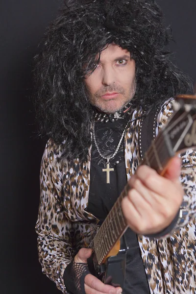 Portrait of middle-aged man wearing leopard skin pattern with guitar over black background — Stock Photo, Image