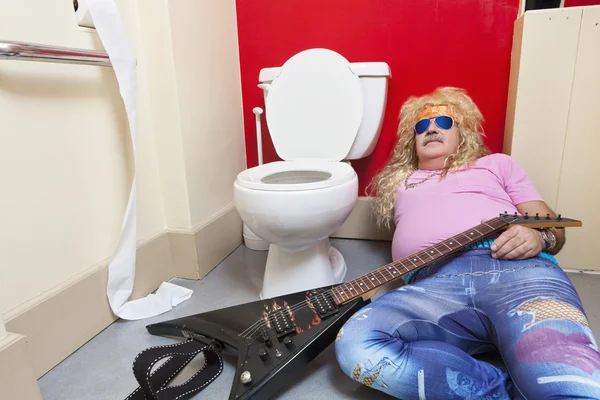 Człowiek leżącej w toalecie z gitarą — Zdjęcie stockowe