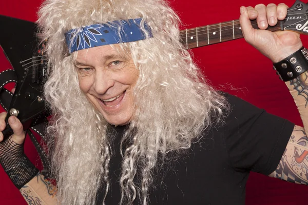 Close-up view of smiling middle-aged man holding guitar behind back — Stock Photo, Image