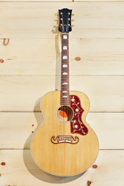 Guitarra acústica con etiqueta en una pared de grano de madera —  Fotos de Stock
