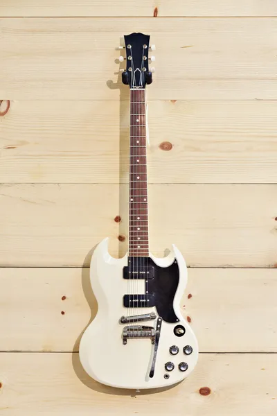 Witte gitaar op houtnerf muur — Stockfoto