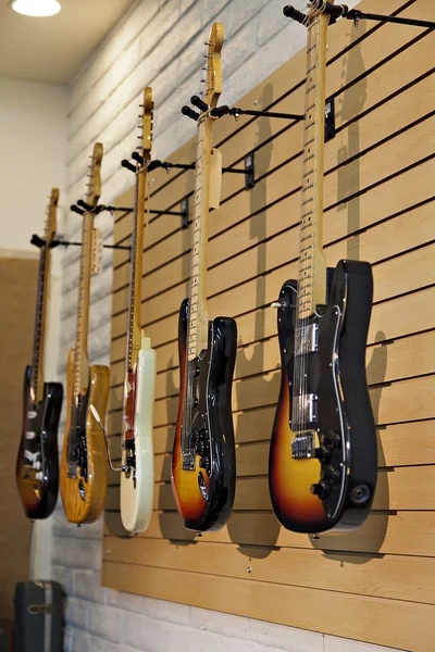 Cinco guitarras elétricas penduradas no rack de exibição na loja para venda — Fotografia de Stock