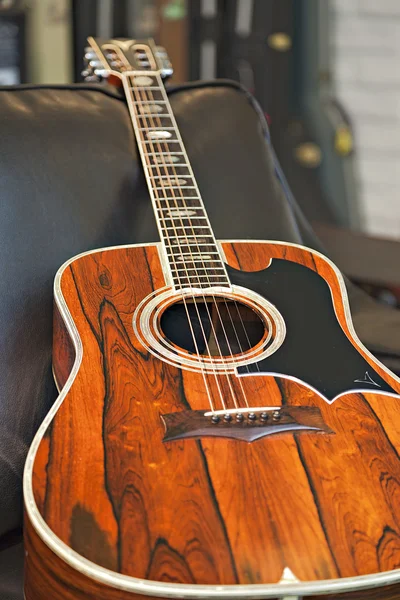 Vista de cerca de la guitarra acústica acostado en el sofá en la tienda de música —  Fotos de Stock