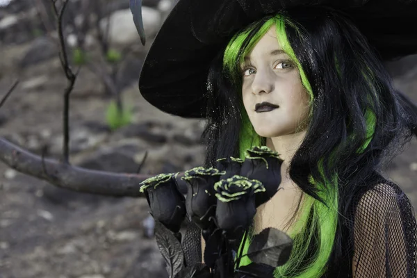 Little witch holding black roses looking away — Stock Photo, Image