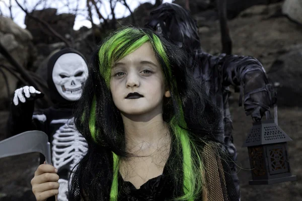 Retrato de menina vestida como bruxa, enquanto seus amigos vestida com traje de esqueleto — Fotografia de Stock