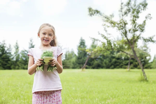 Portrait of a happy girl holding stuffed toy in park — Stock Photo, Image