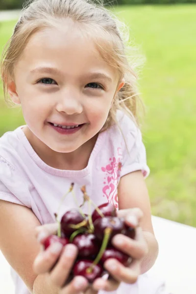Retrato de uma menina feliz com as mãos cheias em bing cerejas — Fotografia de Stock