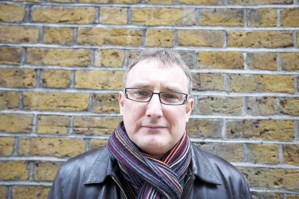 Portrait d'un homme mature portant des lunettes avec écharpe contre mur — Photo
