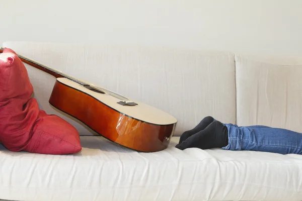 Low section of man's leg with guitar kept on sofa — Stock Photo, Image