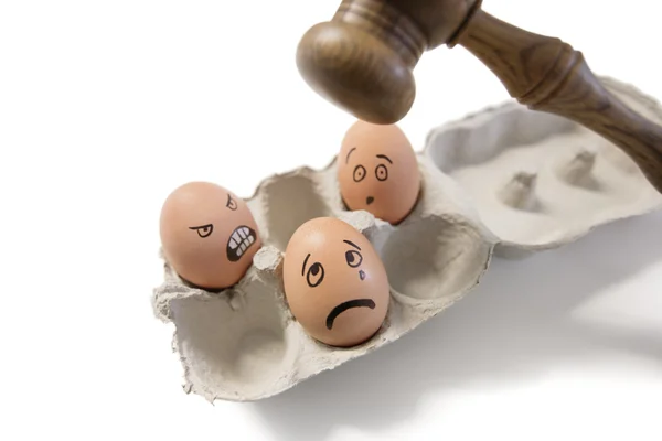 Funny faces on egg with gavel about to hit — Stock Photo, Image