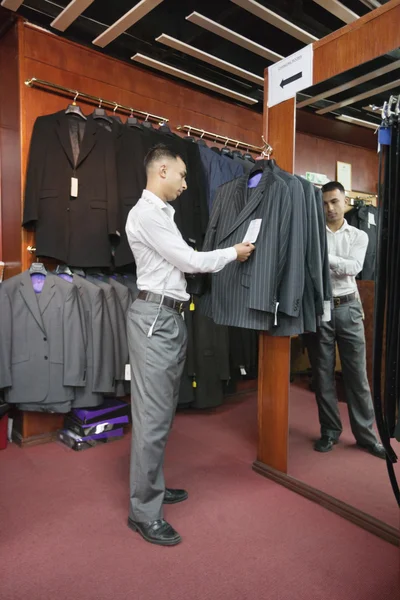 Full-length of tailor standing by the clothing rack of suits — Stock Photo, Image