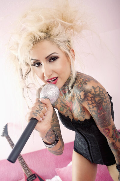 Портрет татуированной блондинки, поющей с микрофоном
