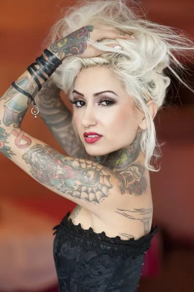 Retrato de jovem tatuada vestindo espartilho com as mãos no cabelo — Fotografia de Stock