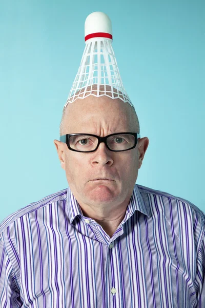 Portrait of angry man with shuttlecock on head over colored background — Stockfoto