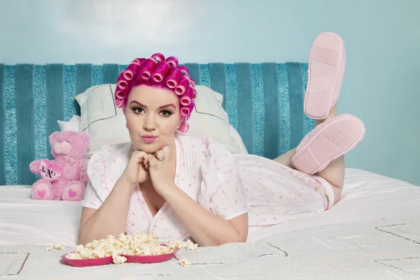 Porträtt av ung kvinna liggande på sängen med popcorn — Stockfoto