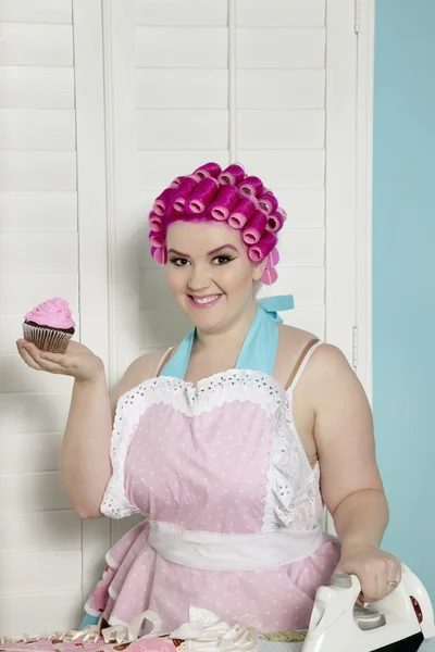 Portret van gelukkige jonge vrouw met cupcake tijdens het strijken — Stockfoto