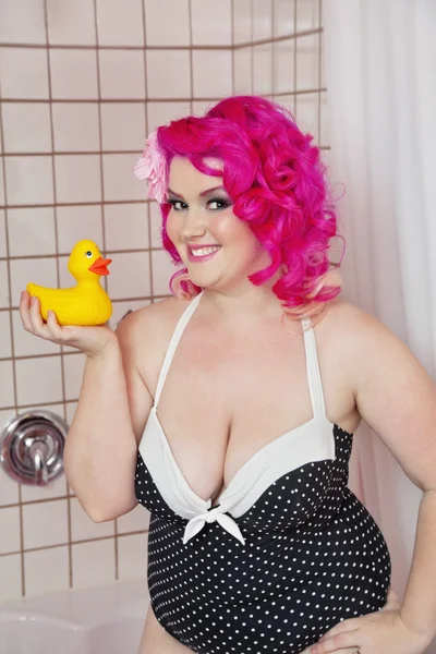 Portrait of a young woman in swimwear holding rubber duck in bathroom — Stock Photo, Image