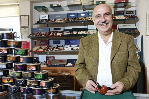 Retrato de un dueño maduro feliz de la tienda del tabaco con las latas en exhibición — Foto de Stock