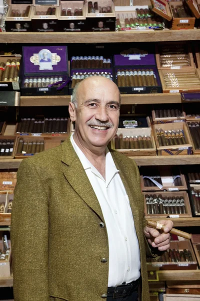Retrato de un propietario masculino de una tienda de tabaco de pie con cajas de cigarros en el fondo — Foto de Stock