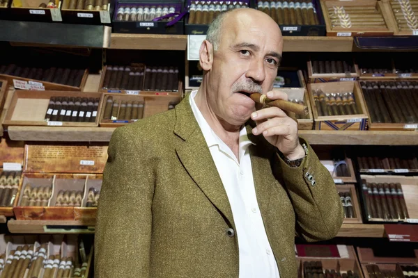 Retrato del dueño maduro de la tienda de tabaco fumando cigarro en la tienda — Foto de Stock