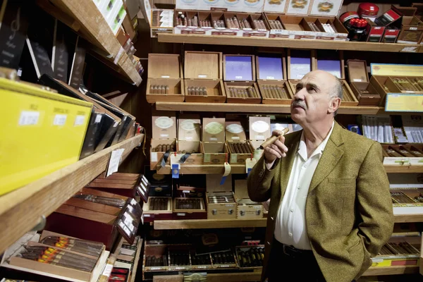 Kis dohány bolt tulajdonosa látszó-nél szivar dobozok kijelző boltban — Stock Fotó