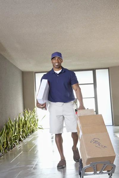 Glad afroamerikanska leverans mannen med paket — Stockfoto