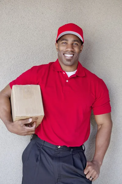 Portrait of a happy young man holding delivery box against wall — Stock Photo, Image