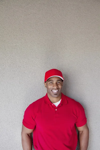 Portrait of a happy African American delivery man against wall — Stock Photo, Image