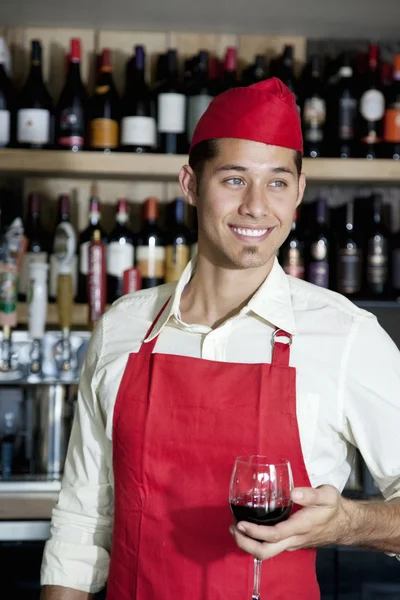 Szczęśliwy przystojny barman trzyma kieliszek wina w barze — Zdjęcie stockowe