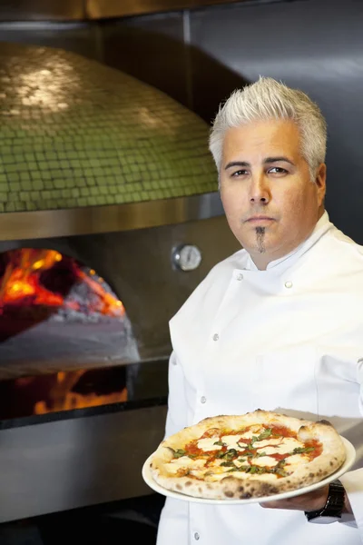 Retrato de um chef adulto médio confiante segurando pizza — Fotografia de Stock