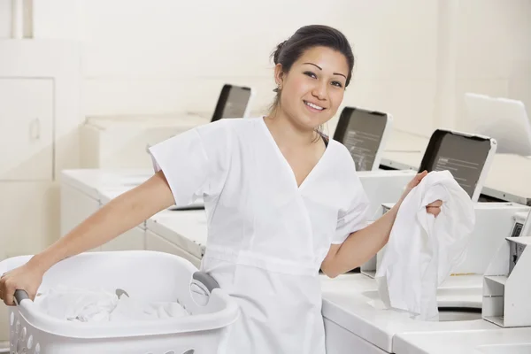 Porträt einer glücklichen jungen Angestellten, die Kleidung in die Waschmaschine legt — Stockfoto