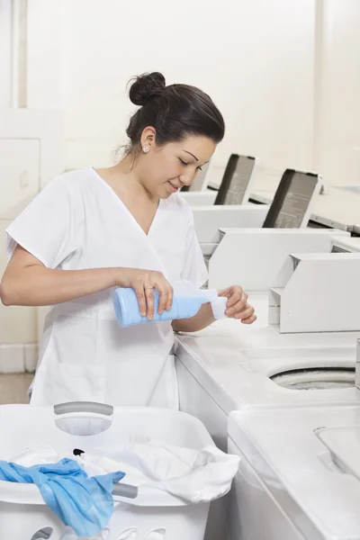 Fröhliche junge Mitarbeiterin gießt Waschmittel in Waschmaschinenwaschsalon — Stockfoto