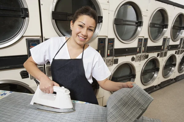 Portrait d'une femme heureuse portant un tablier à repasser devant les machines à laver — Photo