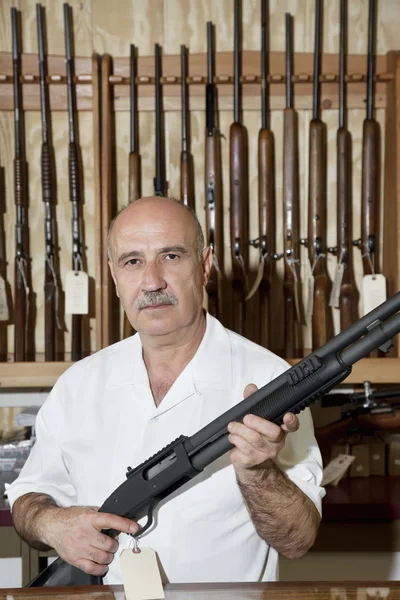 Portrait of a mature gun merchant with rifle — Stock Photo, Image