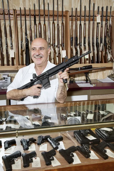 Glücklicher älterer Mann mit Gewehr im Waffengeschäft — Stockfoto