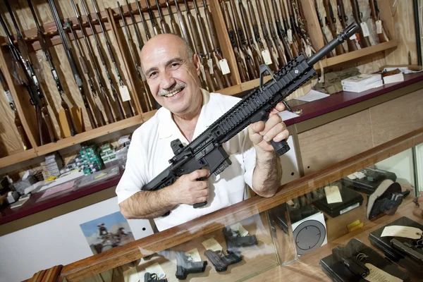 Retrato de un feliz comerciante maduro con rifle en la tienda de armas —  Fotos de Stock