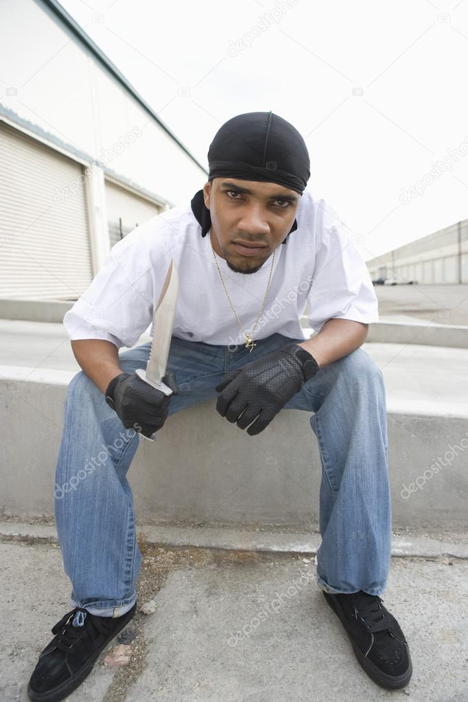 Angry Young Criminal Sitting With Knife On Terrace