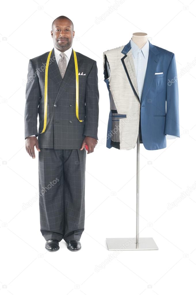 Portrait of tailor in formal wear standing besides a dummy