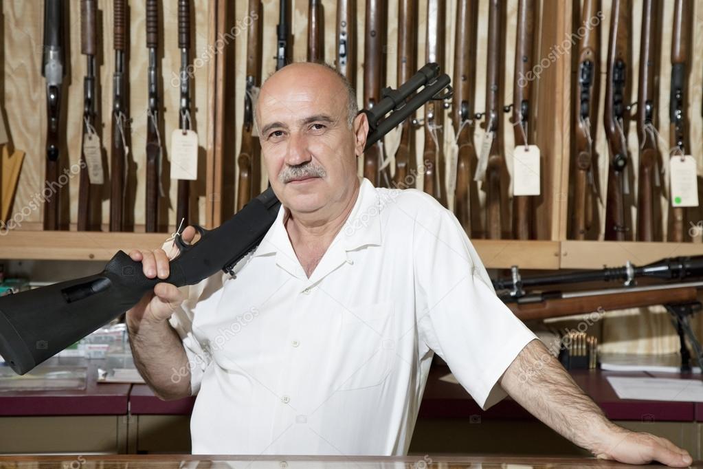 Portrait of a mature man with rifle on shoulder in gun store