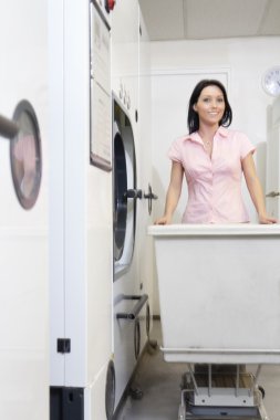 mutlu bir orta çamaşır arabası itme yetişkin kadın portresi
