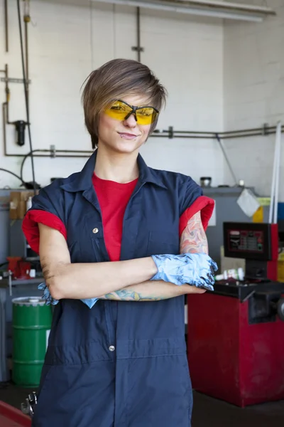 Portrait of a happy mechanic wearing protective gear with arms crossed in auto repair garage — Stock Photo, Image