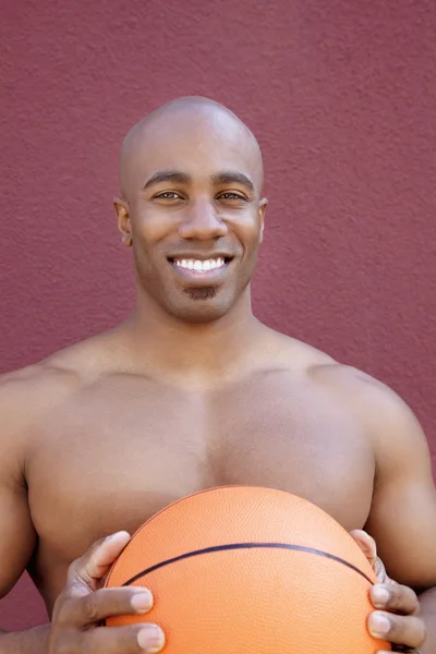 Renkli arka plan üzerinde basketbol ile gömleksiz Afrikalı Amerikalı bir adam portresi — Stok fotoğraf