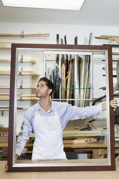 Junger Handwerker schaut in Werkstatt in Rahmecke — Stockfoto