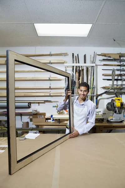 Portrait d'un jeune homme heureux travaillant sur un cadre photo en atelier — Photo