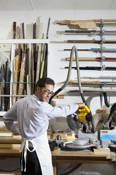 Retrato de un joven mirando hacia atrás mientras usa sierra circular en el taller —  Fotos de Stock