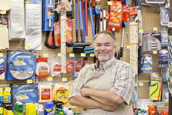 Портрет счастливого взрослого продавца со скрещенными руками в хозяйственном магазине
