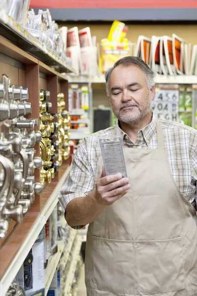 Mature salesperson reading instructions in hardware store — Stock Photo, Image