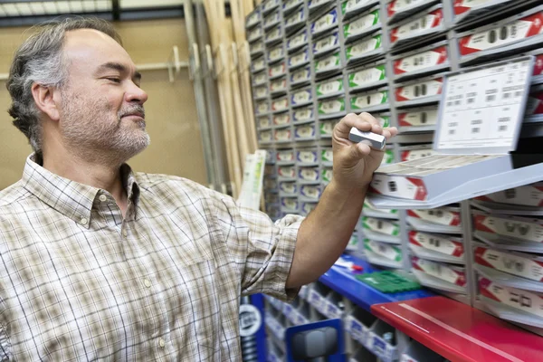 Feliz hombre maduro mirando el paquete de grapas en la tienda — Foto de Stock