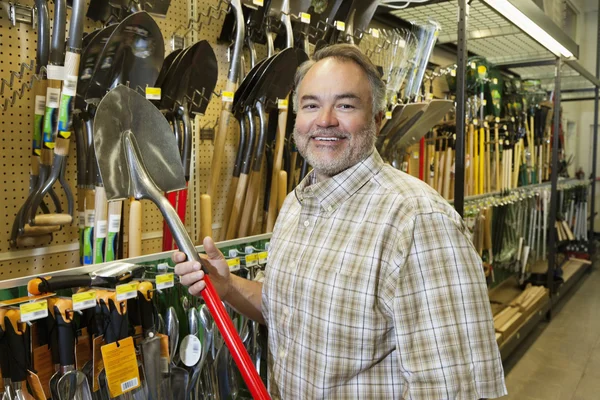 Portret szczęśliwy człowiek dojrzały gospodarstwa łopata w sklepie sprzętu — Zdjęcie stockowe